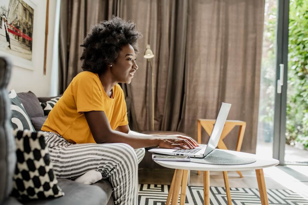 A woman in her living room, reading about the psychology of lottery players on her laptop