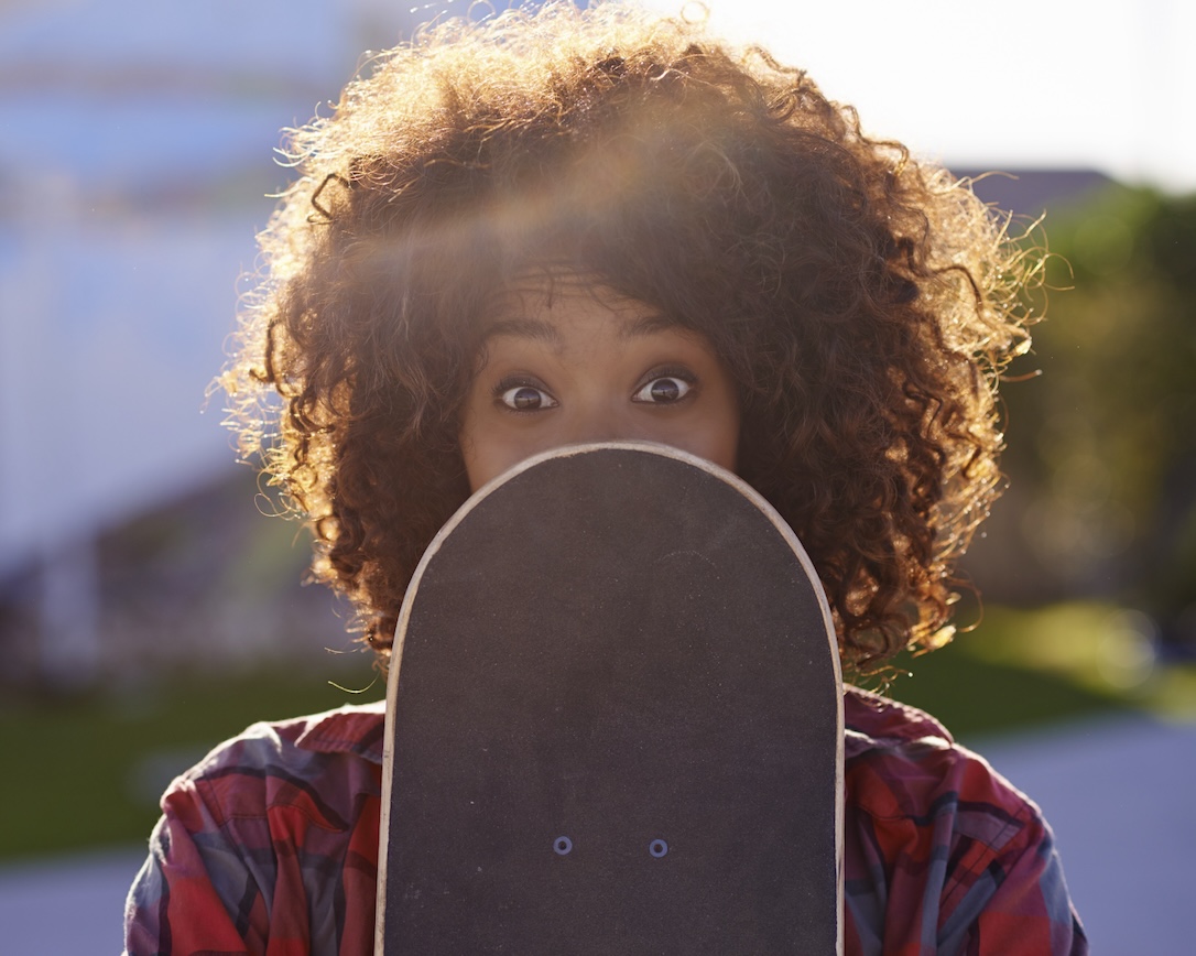 A woman hiding her face behind a skateboard after hearing stories of unclaimed lotto winnings